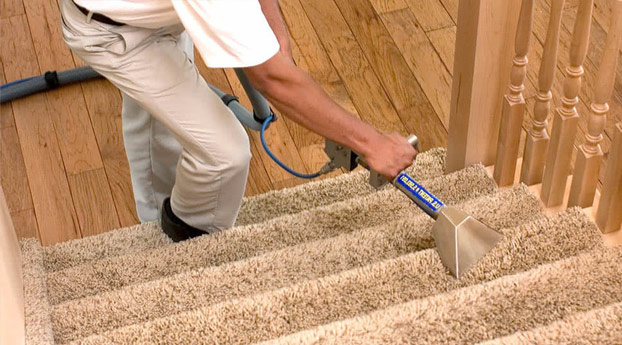 Man vacuuming the carpet inside of a client's home.