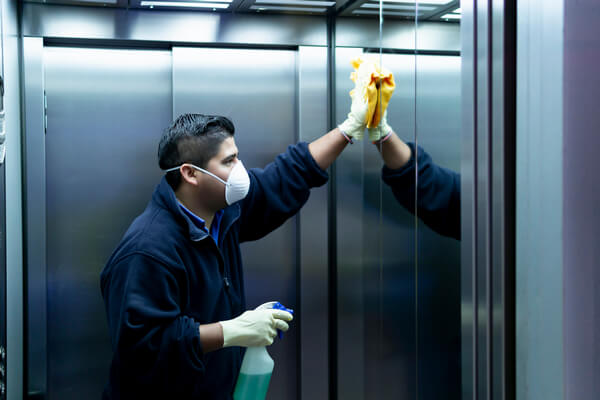 American cleaning employee performing disinfection in an elevator. This is how we clean for health