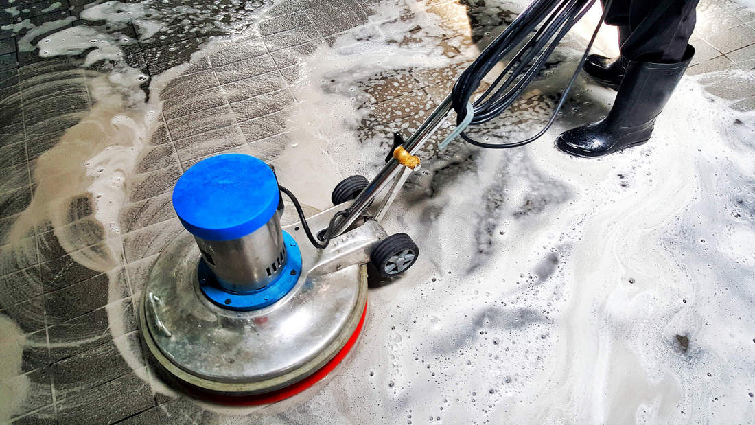 Man with a scrubbing machine cleaning a floor in a business building