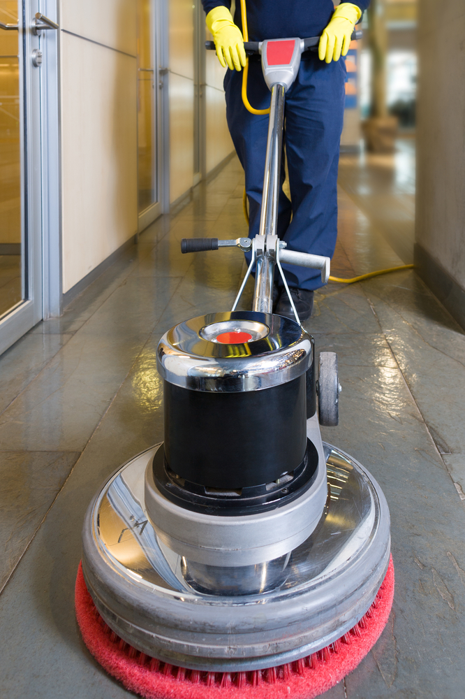 commercial cleaning technician operating a floor cleaning machine on tile floor